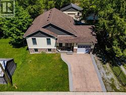 Contemporary residence featuring a combination of siding and stone veneer, an attached garage, a concrete driveway, and mature landscaping with established trees - 