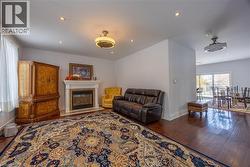 Living area featuring wood-finish flooring, a built-in fireplace with a stone surround, recessed lighting, and a ceiling fan - 