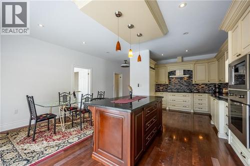 Gourmet kitchen featuring a central island with a dark countertop, extensive cream cabinetry, integrated stainless steel appliances, a tiled backsplash, and recessed lighting - 514 Fishers Glen Road, Vittoria, ON - Indoor Photo Showing Kitchen With Upgraded Kitchen
