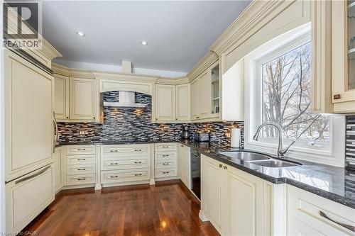 Kitchen featuring cream-colored cabinetry with decorative molding, dark countertops, and a mosaic tile backsplash - 514 Fishers Glen Road, Vittoria, ON - Indoor Photo Showing Kitchen With Double Sink With Upgraded Kitchen
