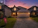 Stately two-story residence featuring a brick and stone facade, covered porch, attached two-car garage with overhead lighting, and arched window details - 21 Davinci Boulevard, Hamilton, ON  - Outdoor 
