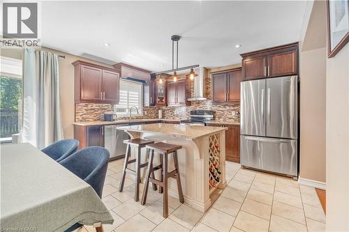Kitchen featuring dark wood cabinetry, stainless steel appliances, a tile backsplash, and a central island with integrated wine storage - 21 Davinci Boulevard, Hamilton, ON - Indoor Photo Showing Kitchen With Stainless Steel Kitchen With Upgraded Kitchen