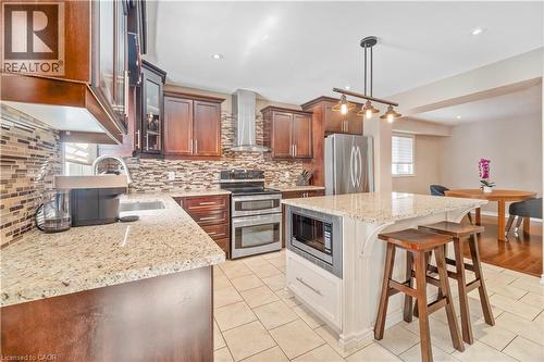 Kitchen featuring wood cabinetry, stainless steel appliances, a multi-tone tile backsplash, and a granite-finish island with integrated microwave - 21 Davinci Boulevard, Hamilton, ON - Indoor Photo Showing Kitchen With Stainless Steel Kitchen With Upgraded Kitchen