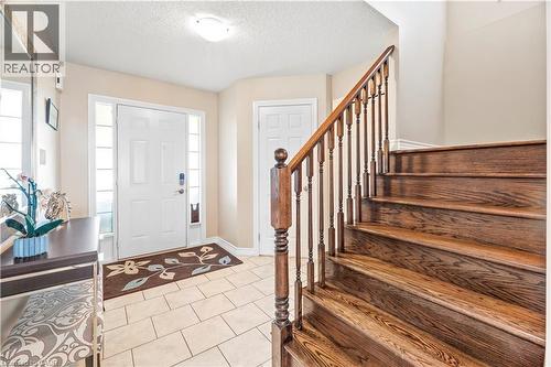 Entryway featuring a solid wood staircase with a turned baluster railing, a tiled floor, and a front door flanked by sidelight windows - 21 Davinci Boulevard, Hamilton, ON - Indoor Photo Showing Other Room