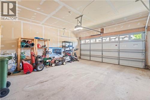 Spacious garage featuring a concrete floor, overhead lighting, and a white paneled garage door with upper window inserts - 21 Davinci Boulevard, Hamilton, ON - Indoor Photo Showing Garage