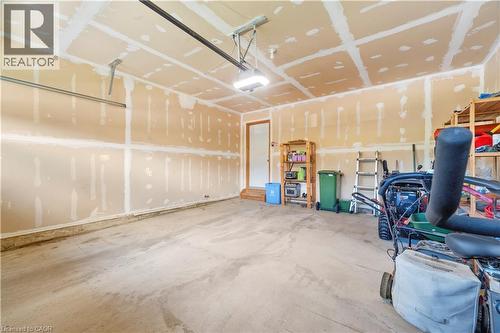 Spacious garage featuring a concrete floor, exposed drywall with taped seams, and an overhead garage door track system - 21 Davinci Boulevard, Hamilton, ON - Indoor Photo Showing Garage
