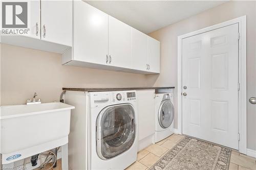 Dedicated laundry area featuring a utility sink, white upper cabinetry, and a dark countertop - 21 Davinci Boulevard, Hamilton, ON - Indoor Photo Showing Laundry Room