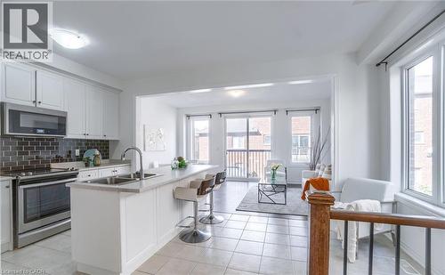 Bright kitchen featuring white cabinetry, stainless steel appliances, a subway tile backsplash, and an island with bar seating - 14 Faye Street, Brampton, ON - Indoor Photo Showing Kitchen With Double Sink With Upgraded Kitchen