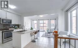 Bright kitchen featuring white cabinetry, stainless steel appliances, a subway tile backsplash, and an island with bar seating - 