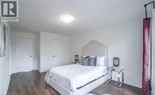 Bedroom featuring wood-finish flooring, two panel doors with black hardware, and a ceiling-mounted light fixture - 14 Faye Street, Brampton, ON - Indoor Photo Showing Bedroom