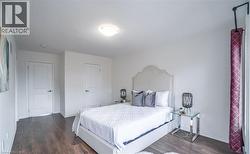 Bedroom featuring wood-finish flooring, two panel doors with black hardware, and a ceiling-mounted light fixture - 
