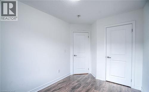 Interior room featuring wood-finish flooring, white baseboards, and two solid panel doors with chrome hardware - 14 Faye Street, Brampton, ON - Indoor Photo Showing Other Room
