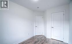 Interior room featuring wood-finish flooring, white baseboards, and two solid panel doors with chrome hardware - 