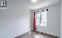 Room featuring wood-finish flooring, white baseboards, and neutral wall paint - 
