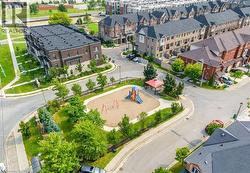 Community green space featuring a sandbox play area with a slide and swings, surrounded by mature trees and paved walkways - 