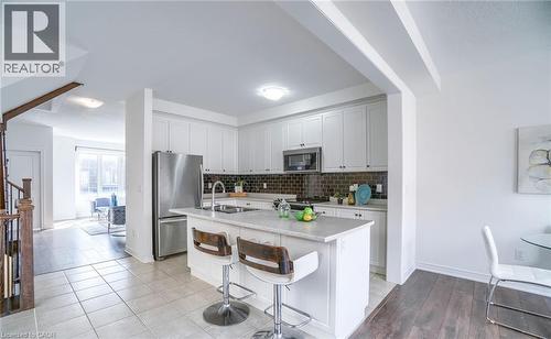 Contemporary kitchen with white cabinetry, stainless steel appliances, and a dark tile backsplash - 14 Faye Street, Brampton, ON - Indoor Photo Showing Kitchen With Stainless Steel Kitchen With Double Sink