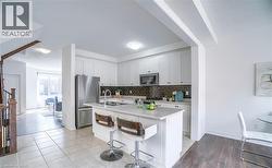 Contemporary kitchen with white cabinetry, stainless steel appliances, and a dark tile backsplash - 