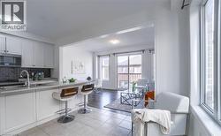 Kitchen featuring white cabinetry, stainless steel appliances, a dark tile backsplash, and a breakfast bar with seating - 