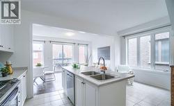 Open-concept kitchen featuring white cabinetry, a double basin sink, and tile flooring - 