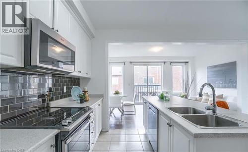 Kitchen featuring white cabinetry, a dark subway tile backsplash, stainless steel appliances, and a double basin sink - 14 Faye Street, Brampton, ON - Indoor Photo Showing Kitchen With Double Sink With Upgraded Kitchen