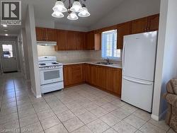 Kitchen featuring tile flooring, wood-finish cabinetry, light countertops, and a tile backsplash - 