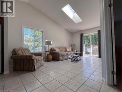 Vaulted ceiling living area featuring a large skylight, a window with exterior views, and tile flooring - 