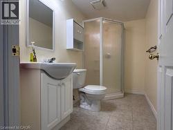 Three-piece Bathroom featuring a white vanity with integrated sink, a corner shower enclosure, toilet, and light-toned tile flooring - 