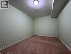 Den with a Door  featuring light green walls, brown carpeting, white baseboards, and a flush mount ceiling light fixture - 