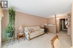 Carpeted living area with neutral wall tones, a partial wall separation, and a chandelier fixture - 