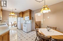 Kitchen featuring wood cabinetry, white appliances, patterned tile flooring, and light countertops - 