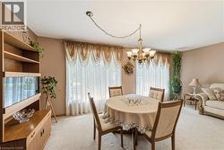 Spacious dining area featuring a brass chandelier, light-toned wall paint and light carpeting - 