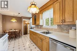Kitchen featuring breakfast nook, natural wood cabinetry, light-toned countertops, and a stainless steel dishwasher, stairs off to the side for separate side entrance - 