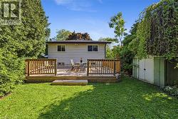 Expansive green lawn with newer, full sized wood deck, surrounded by mature trees and natural landscaping. Original shed. - 