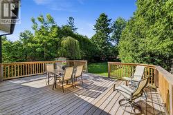 Spacious newer wooden deck with natural wood railing, overlooking a manicured lawn and mature perimeter trees - 