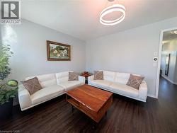 Spacious living area featuring dark wood-finish flooring, a contemporary circular pendant light fixture, and light-toned wall paint - 
