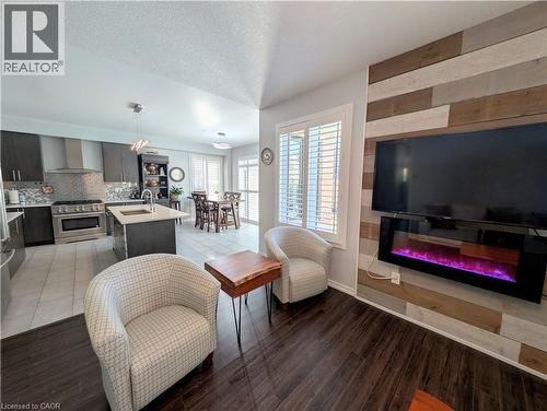 Open-concept living area featuring rich wood-finish flooring and a fireplace with a multi-tone wood-paneled accent wall - 37 Mull Avenue, Caledonia, ON - Indoor