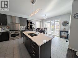 Modern kitchen featuring a spacious island with an undermount double sink, light-toned countertop, and dark wood-finish cabinetry - 