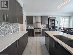 Contemporary kitchen featuring dark wood-finish cabinetry, light-toned countertops, a mosaic tile backsplash, stainless steel appliances, and a central island with an undermount sink - 