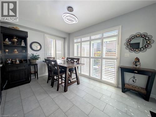 Dining area featuring light-toned tile flooring, white plantation shutters, and a modern circular ceiling light fixture - 37 Mull Avenue, Caledonia, ON - Indoor Photo Showing Dining Room