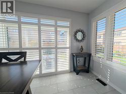 Light gray tiled flooring, white plantation shutters, and a sliding glass door - 