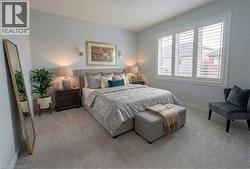 Soft gray wall color with recessed lighting, plush carpet flooring, and a large window with white plantation shutters - 