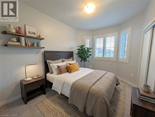 Bedroom featuring a bay window with white plantation shutters, dark wood-finish headboard, built-in shelving, carpet flooring, and a mirrored closet door - 37 Mull Avenue, Caledonia, ON - Indoor Photo Showing Bedroom