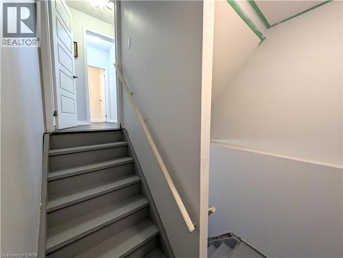 Staircase with a wood handrail, painted treads, and light gray walls - 37 Mull Avenue, Caledonia, ON - Indoor Photo Showing Other Room