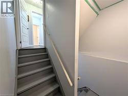 Staircase with a wood handrail, painted treads, and light gray walls - 
