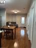 Wood-finish flooring extends throughout this open living space, featuring recessed and flush-mount lighting, a white entry door with decorative glass inserts, and a stainless steel refrigerator - 179 Vine Street S, St. Catharines, ON  - Indoor Photo Showing Other Room 
