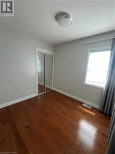 Room featuring wood-finish flooring, a window with natural light, and a mirrored closet - 179 S Vine Street S, St. Catharines, ON 