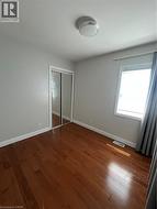 Room featuring wood-finish flooring, a window with natural light, and a mirrored closet - 