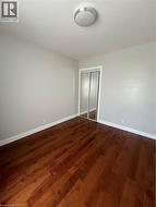 Rich wood-finish flooring provides a warm foundation for this room, featuring light gray walls, white baseboards, and a semi-flush mount ceiling light - 