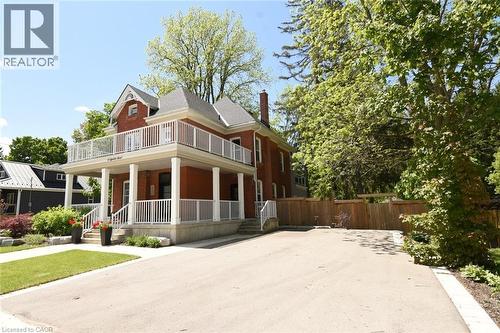 Red brick exterior featuring a full-width covered porch with white columns and railings. Also showing private double wide driveway - 89 Lynden Road, Lynden, ON 