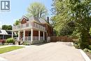 Red brick exterior featuring a full-width covered porch with white columns and railings. Also showing private double wide driveway - 89 Lynden Road, Lynden, ON 